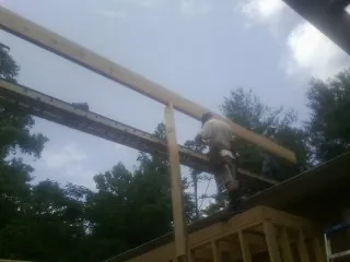 Carpenter setting a ridge beam over a new addition frame — Ice Dam Removal by Roofing Brothers in Cofield