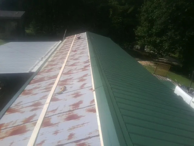 Old rusted panels beside newly installed green metal roofing — Wind Damage Roof Repair by Roofing Brothers in Cofield