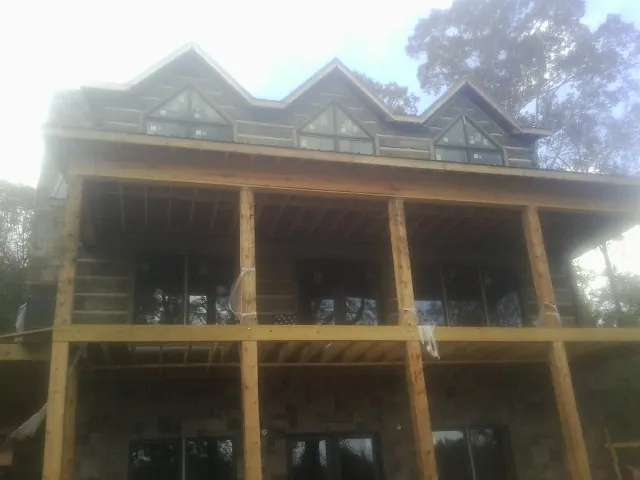 Dormers and porch framing on a large log home under construction — Roof Coating work by our crew in Cofield