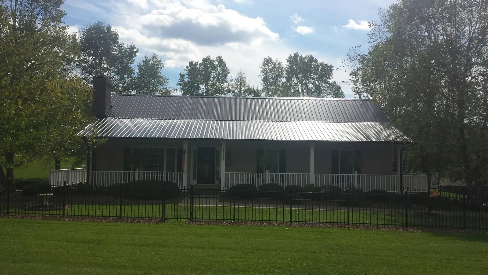 Gray metal roof on a brick ranch with a full width front porch — Gutter Guard Installation work by our crew in Cofield