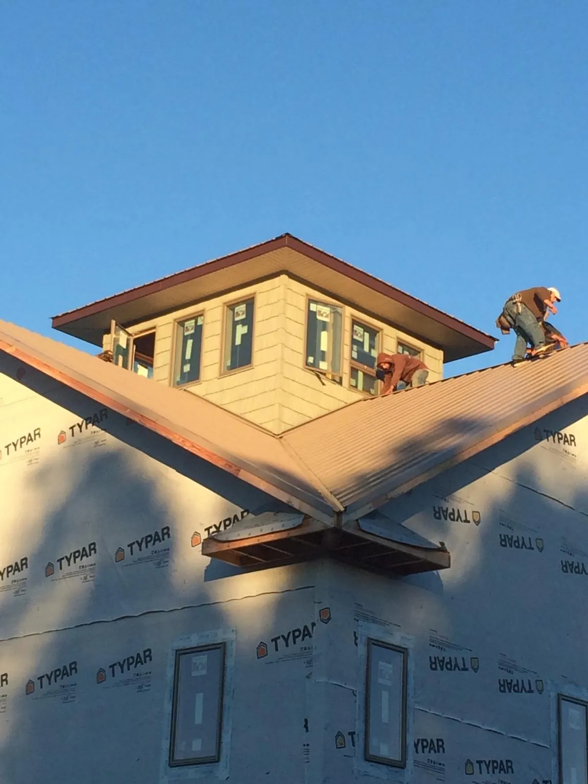 Roofers working around a rooftop cupola on a new metal roof at sunset — Roof Waterproofing in Cofield by Roofing Brothers